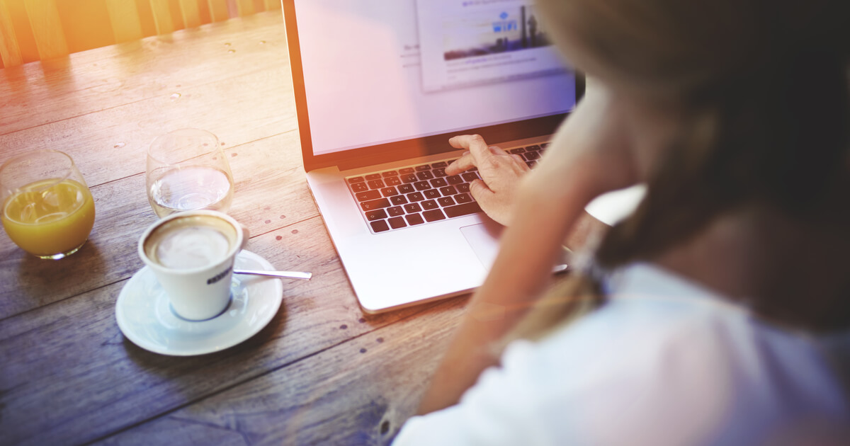 Junge Frau sitzt in einem Café und arbeitet an einem Laptop